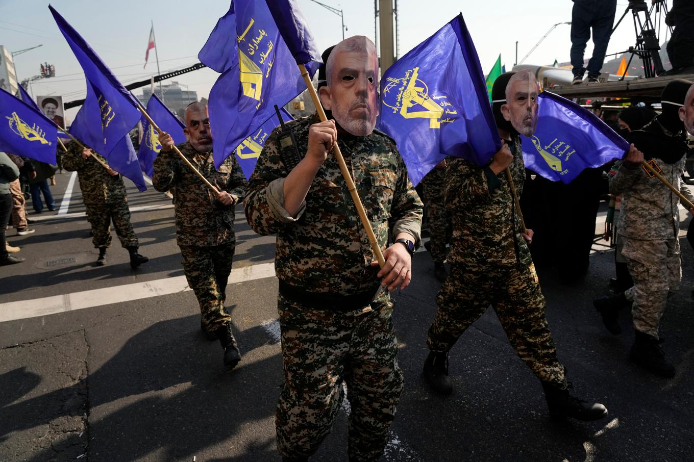 Medlemmar i den iranska milisstyrkan Basij med Revolutionsgardets flagga och ansiktsmasker föreställande den dödade Hamasledaren Yahya Sinwar under en parad i Teheran i förra veckan. Foto: Vahid Salemi/AP/TT