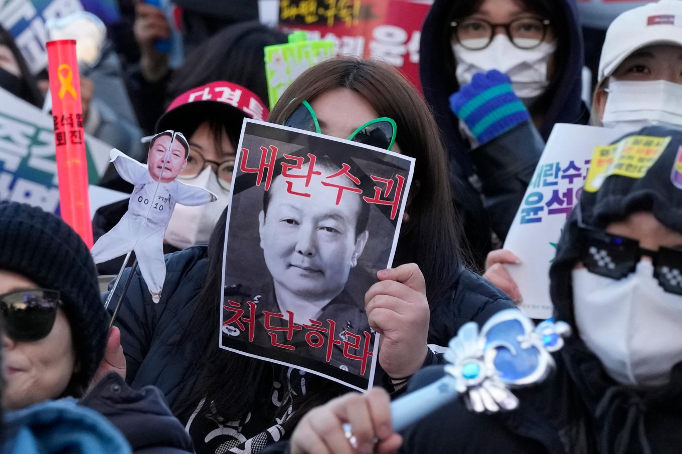 En demonstrant håller upp ett plakat med foto på den sydkoreanske presidenten Yoon Suk-Yeol med krav på hans avgång. Foto: Ahn Young-joon/AP/TT