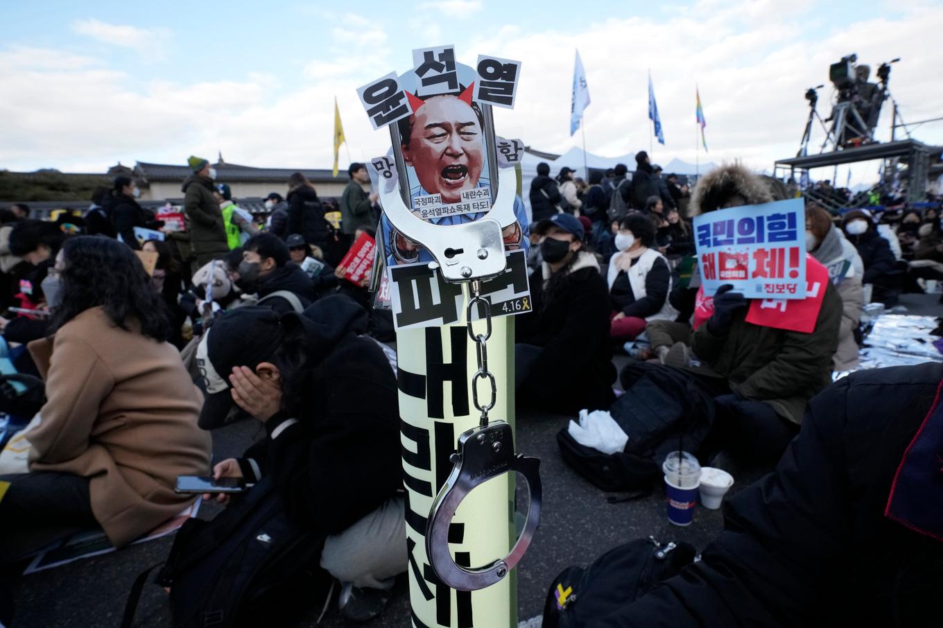 En demonstrant håller upp ett plakat med foto på den sydkoreanske presidenten Yoon Suk-Yeol med krav på hans avgång. Foto: Ahn Young-Joon/AP/TT