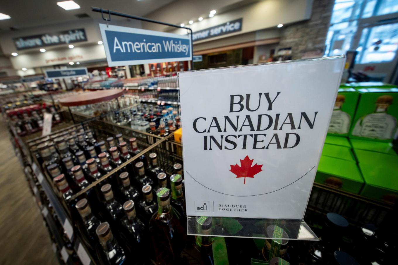 En skylt framför en hylla med amerikansk whisky på en spritaffär i Vancouver manar konsumenterna att välja kanadensiskt i stället. Foto: Ethan Cairns/AP/TT