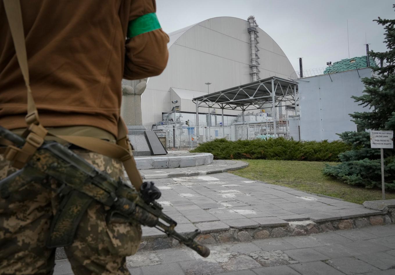 En ukrainsk soldat framför sarkofagen som skyddar Tjernobyls reaktor fyra, på en bild tagen i april 2022. Foto: Efrem Lukatsky/AP/TT