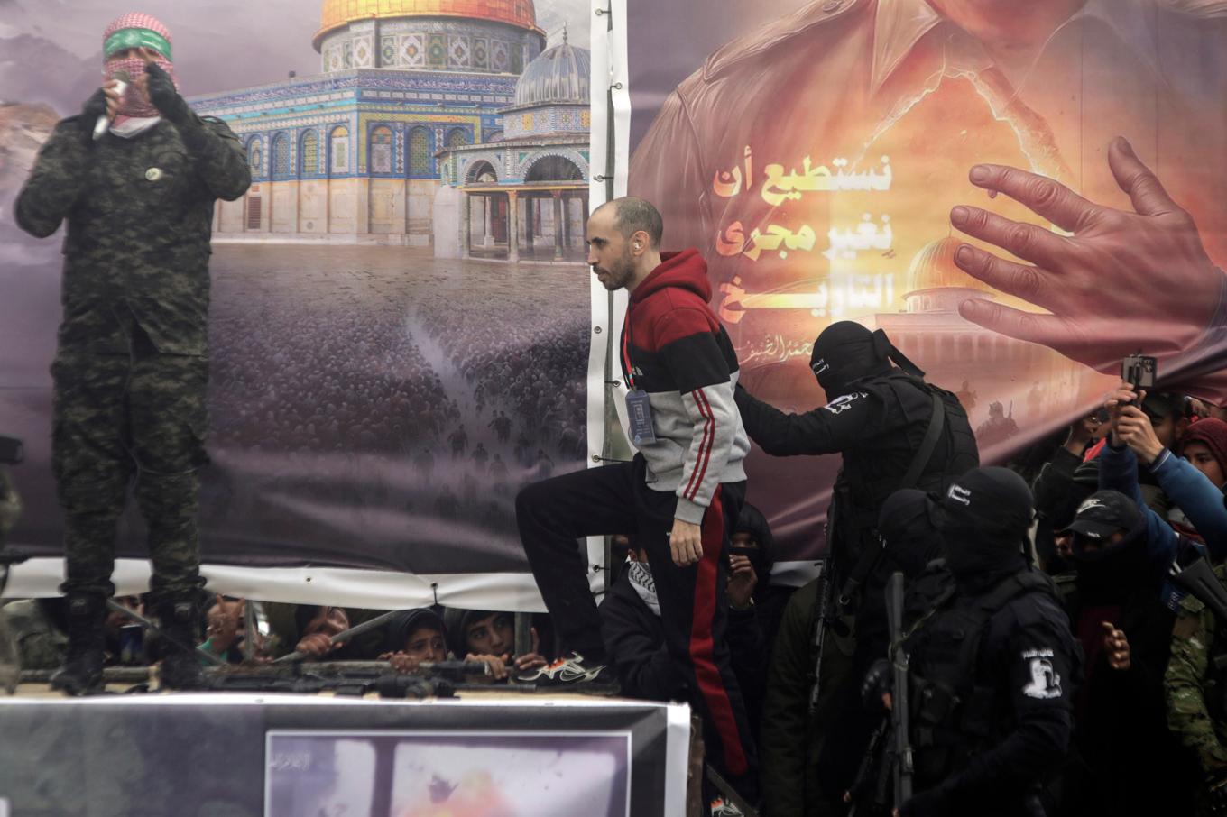 Israelen Tal Shoham eskorteras av Hamas upp på scen innan han lämnas över till Röda korset i Rafaah. Foto: Jehad Alshrafi/AP/TT