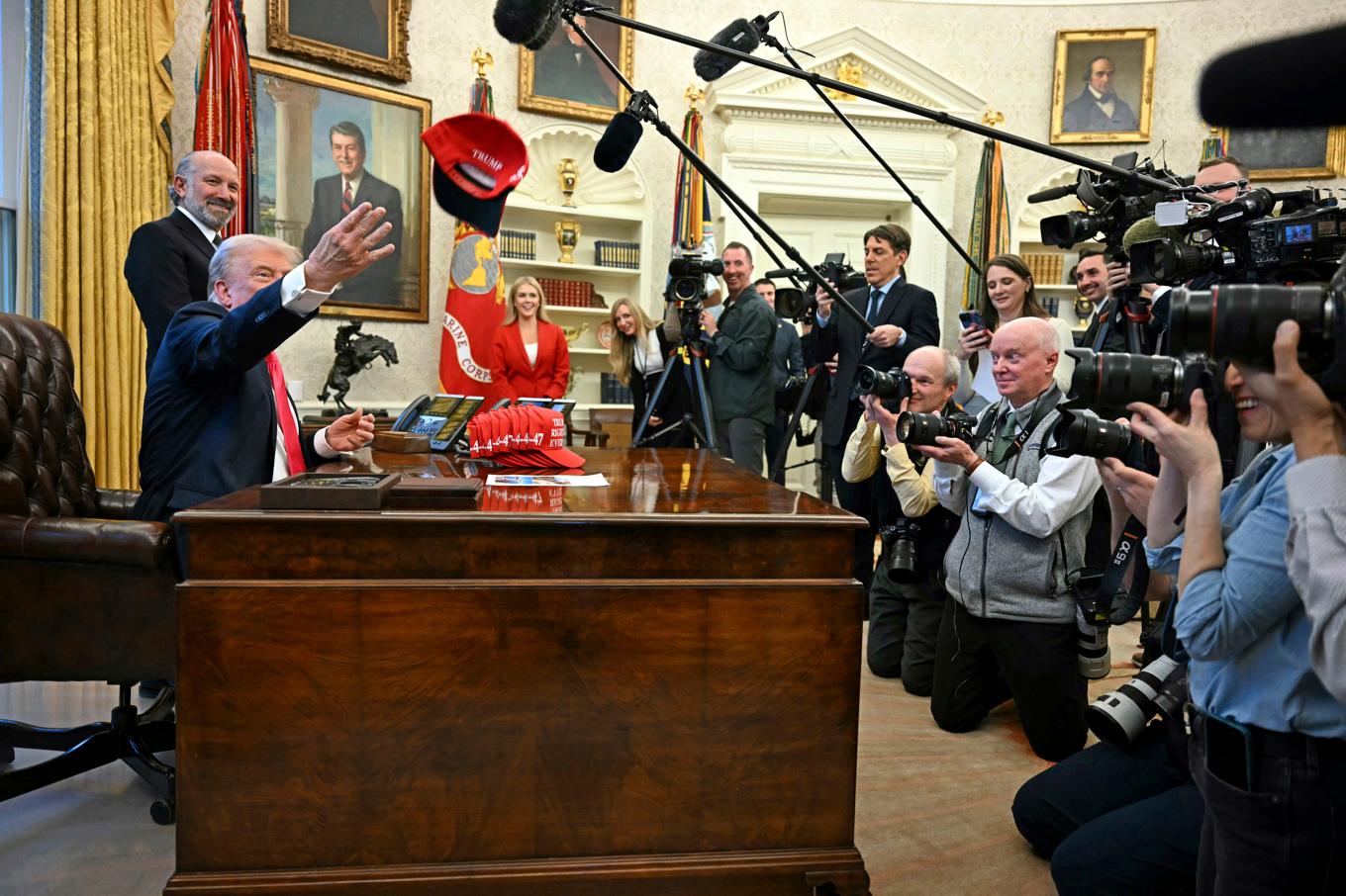 President Donald Trump kastar en keps med texten "Trump hade rätt om allt" medan han talar till reportrar i Ovala rummet i Vita huset på tisdagen. Foto: Pool via AP/TT