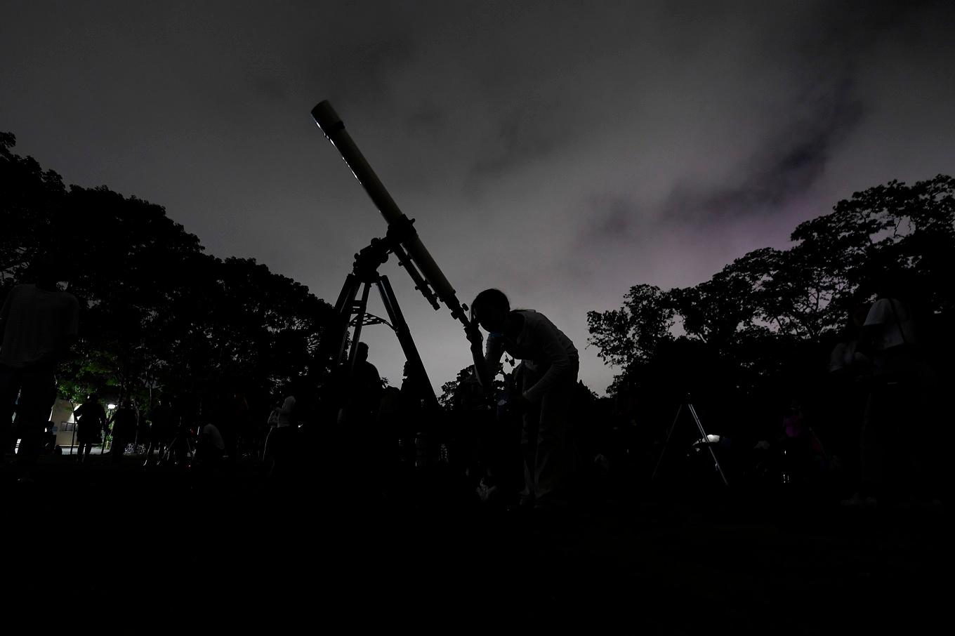 En flicka tittar genom ett teleskop på en parad av fem planeter i Venezuela 2023. I kväll kan sju planeter ses rada upp sig på himlen. Arkivbild. Foto: Matias Delacroix/AP/TT