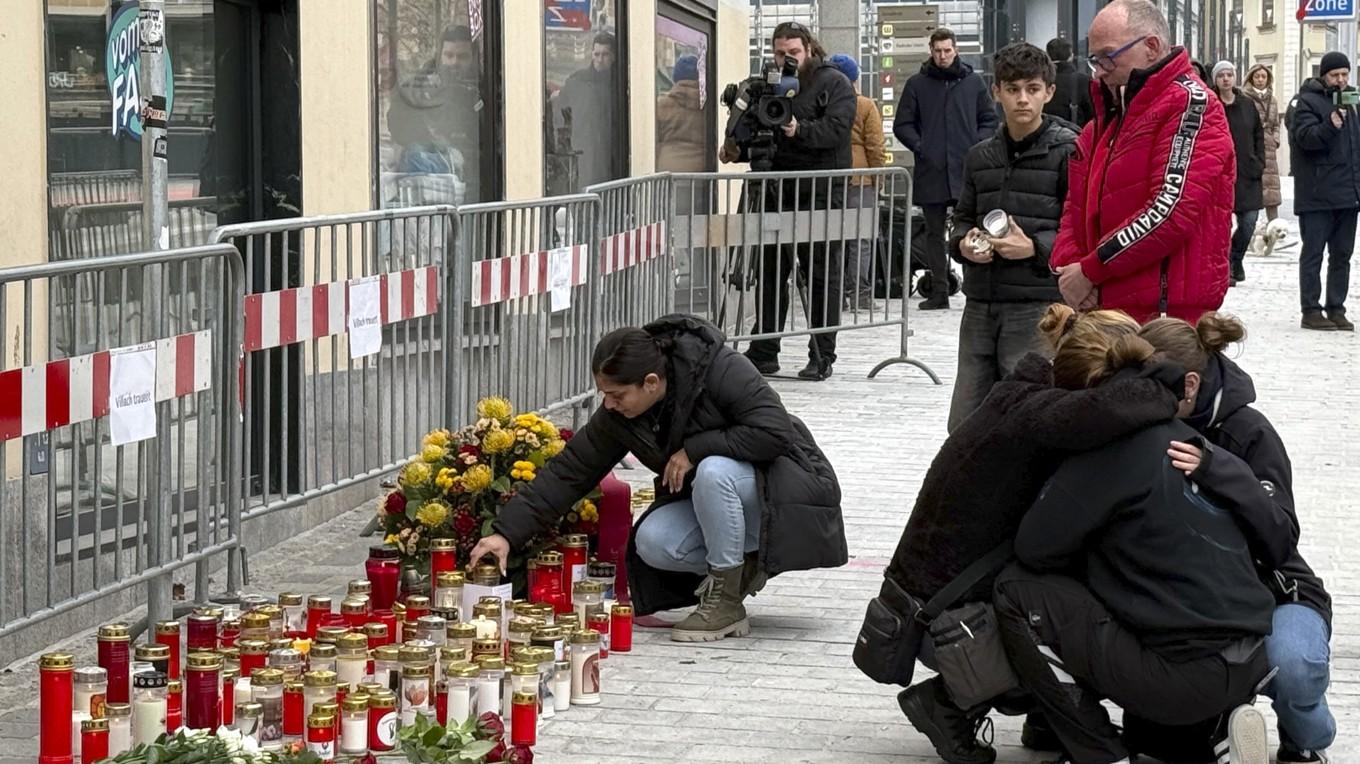 Människor sörjer den 16 februari vid en provisorisk minnesplats med ljus och blommor på den plats där en man slumpmässigt attackerade förbipasserande med kniv och högg ihjäl en tonåring och skadade fem andra personer i Villach i Österrike. Foto: Gerd Eggenberger/APA/AFP via Getty Images