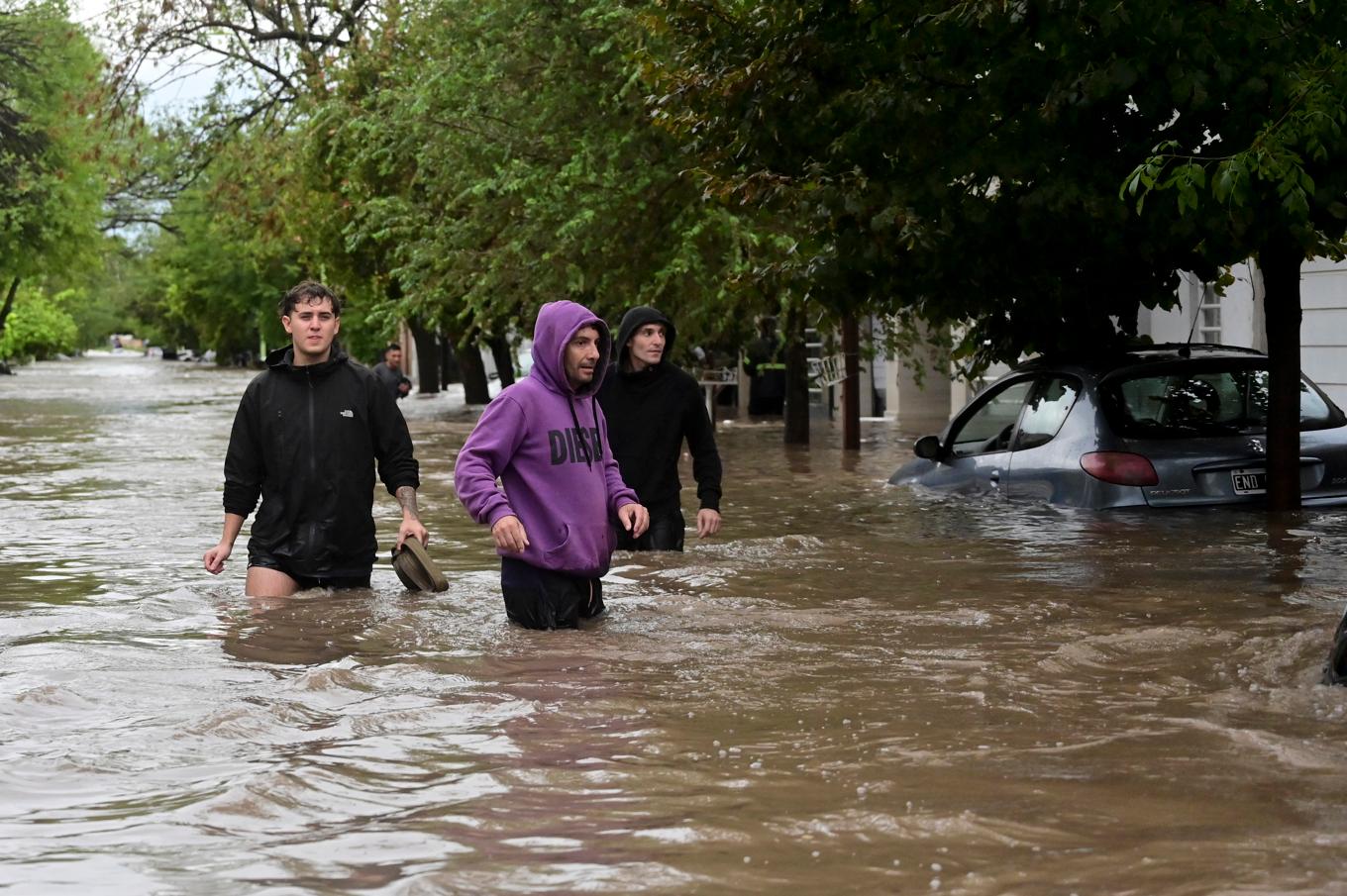 Människor vadar längs en översvämmad gata i argentinska Bahía Blanca, en hamnstad med 350 000 invånare, på fredagen. Foto: Juan Sebastian Lobos/AP/TT