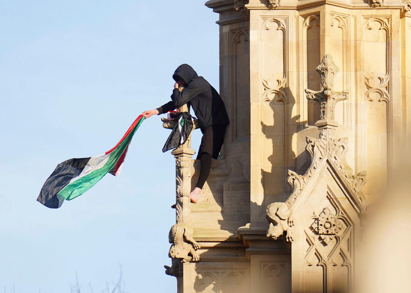 En man viftar med en palestinsk flagga från klocktornet Big Ben. Foto: James Manning/AP/TT