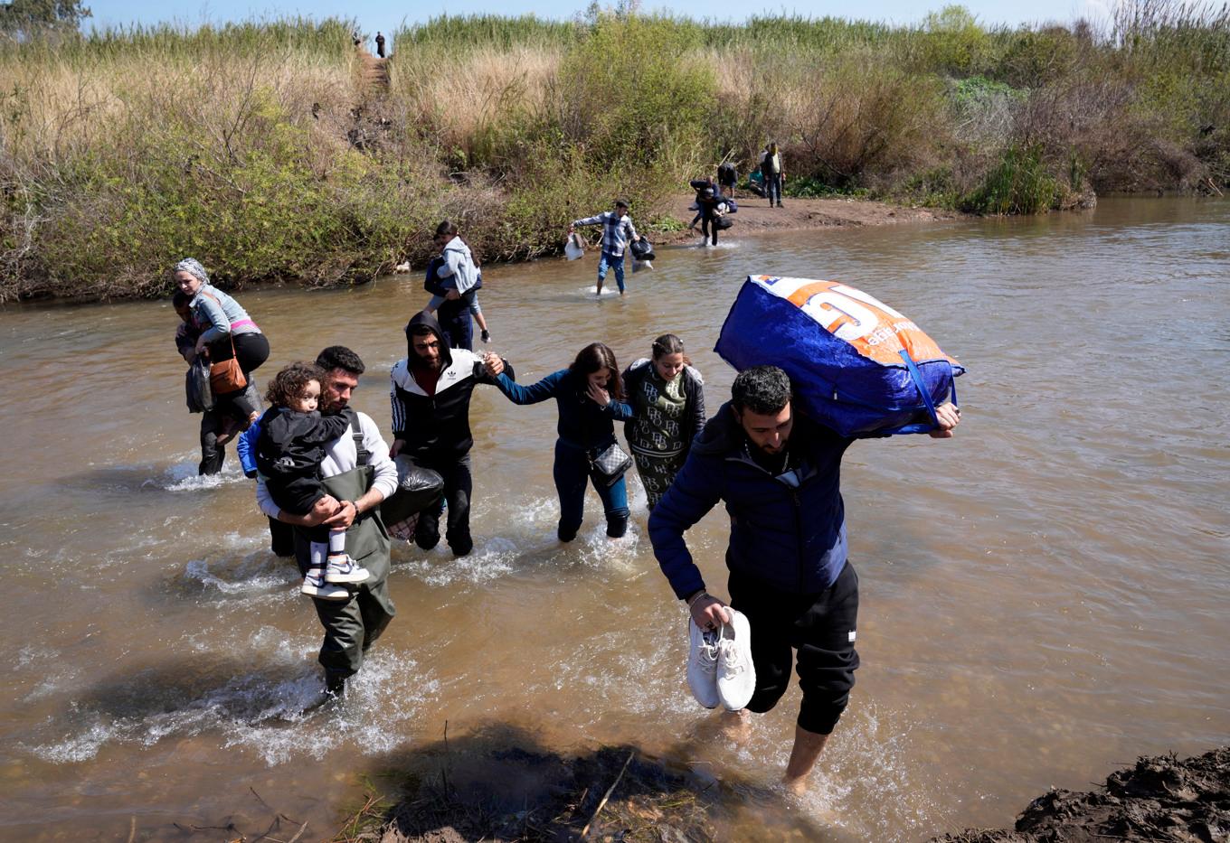 Syriska familjer som flytt striderna i Syrien korsar en flod som markerar gränsen mellan Syrien och norra Libanon. Bild från tisdagen den 11 mars 2025. Foto: Hussein Malla/AP/TT