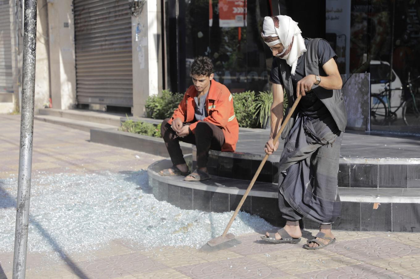 Invånare i Jemens huvudstad Sanaa städar krossat glas efter de amerikanska attackerna. Foto: Osama Abd al-Rahman/AP/TT