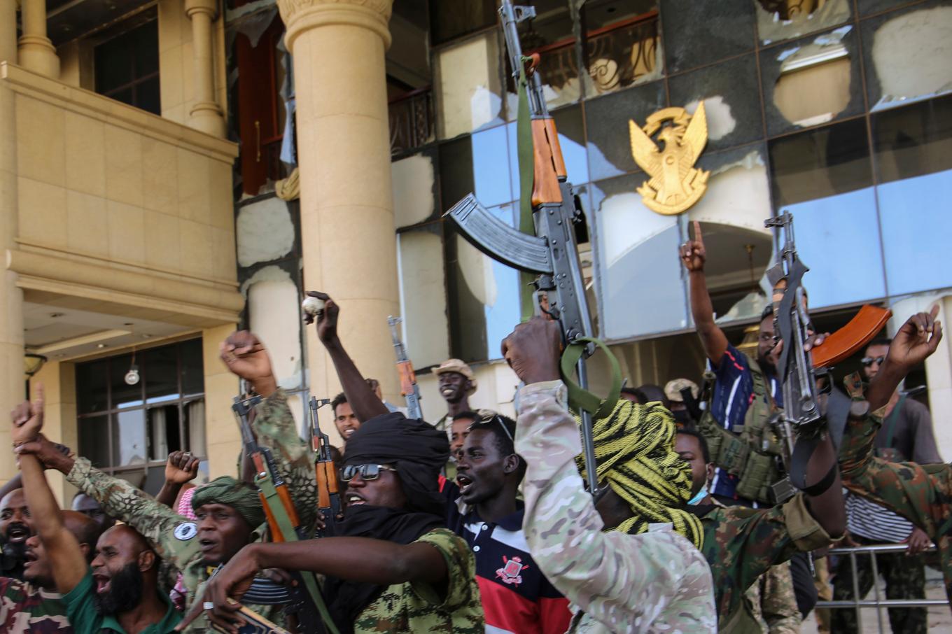 Soldater firar återtagandet av presidentpalatset i Khartum, Sudan. Under lördagen uppges även centralbanken vara under arméns kontroll. Foto: AP/TT