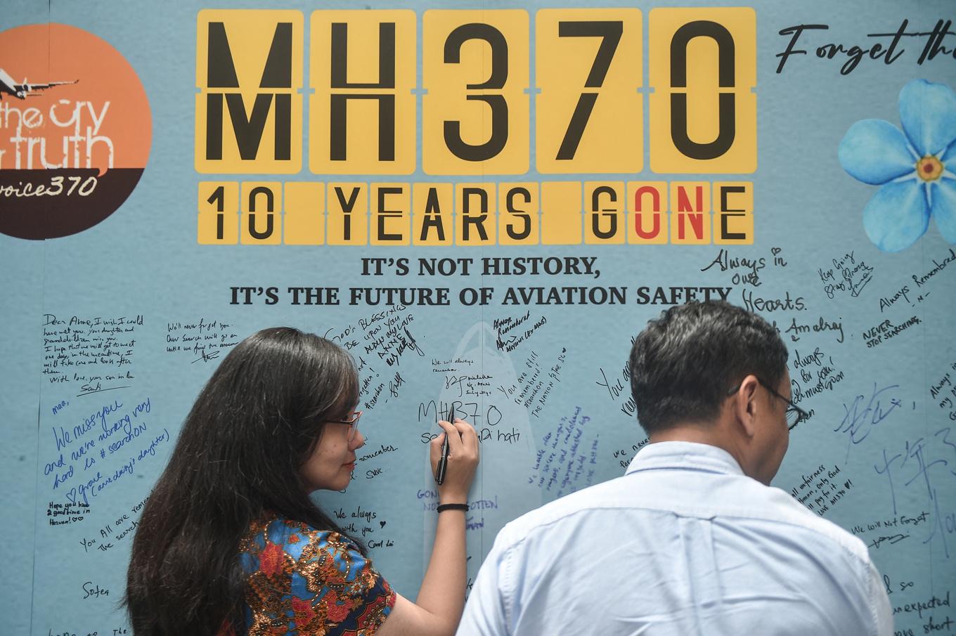 Människor skriver på en minnesvägg för Malaysia Airlines flight MH370 i mars 2024. Flygplanets försvinnande är ett av de mest gåtfulla i den kommersiella flygtrafikens historia. Foto: Arif Kartono/AFP via Getty Images