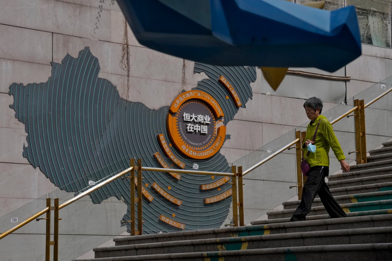 Kvinna passerar en karta över Evergrandes utvecklingsprojekt i Kina hösten 2023. Arkivbild Foto: Andy Wong AP/TT