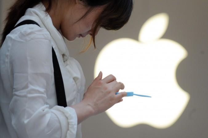 En kvinna på en Apple-affär i Shanghai kollar sin mobiltelefon. Allt fler kineser får sina nyheter från sociala medier, precis som i resten av världen, och nu slår regimens censurapparat till mot detta. (Foto: Peter Parks/AFP/Getty Images)