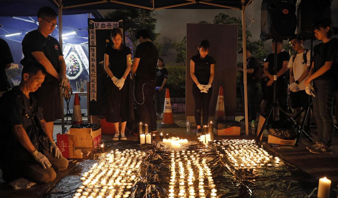 Människor sörjer en kvinnas död i Hongkong den 6 juli 2019. Kvinnan tog enligt uppgifter sitt liv på grund av missnöje med Hongkongs styre. Foto: Vincent Yu/AP/TT