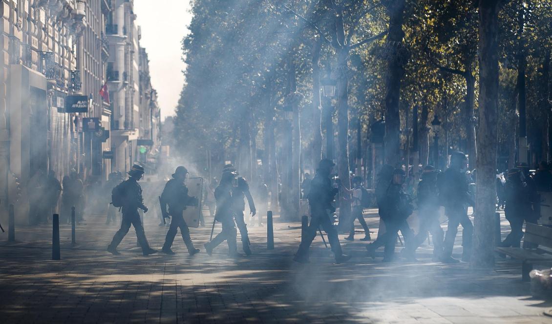 Kravallpolis på Champs-Élysées efter att tårgas använts mot demonstranter i Paris. Foto: Kamil Zihnioglu/AP/TT