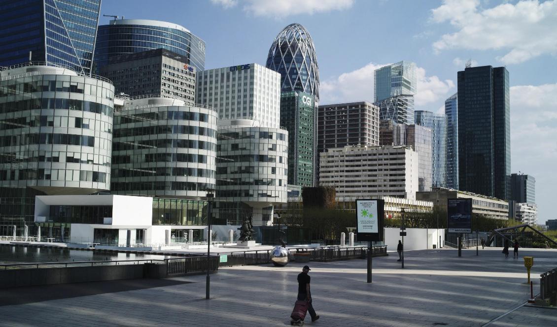 Ett fåtal personer passerar i övrigt folktomma affärskvarter i La Défense, Paris. Foto: Thibault Camus/AP/TT