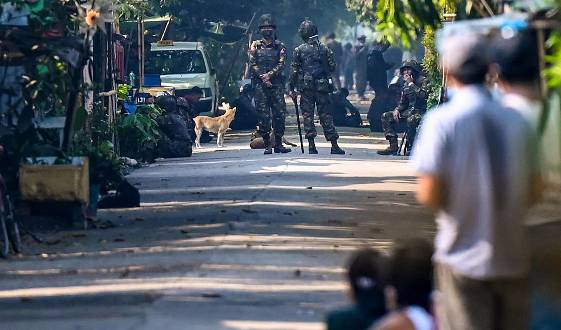 
Myanmarbor tittar på när militär blockerar en väg i Yangon den 10 mars 2021. Foto: STR/AFP via Getty Images                                            