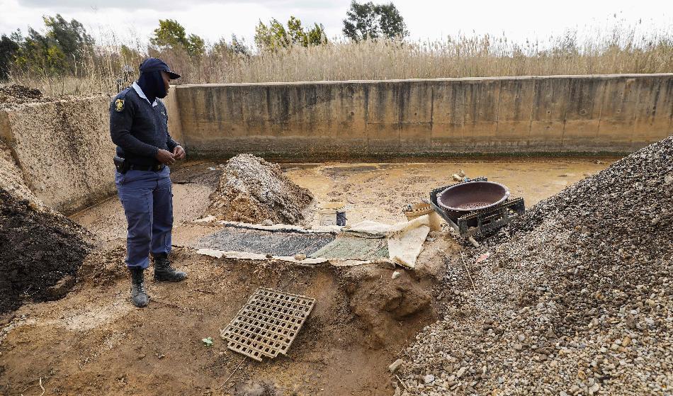 

En sydafrikansk polis betraktar en illegal gruva som använts för att utvinna guld nära Harmony Gold Mining Operations Operations i Randfontein, den 2 augusti. Foto: Phil Magakoe/AFP via Getty Images                                                                                        