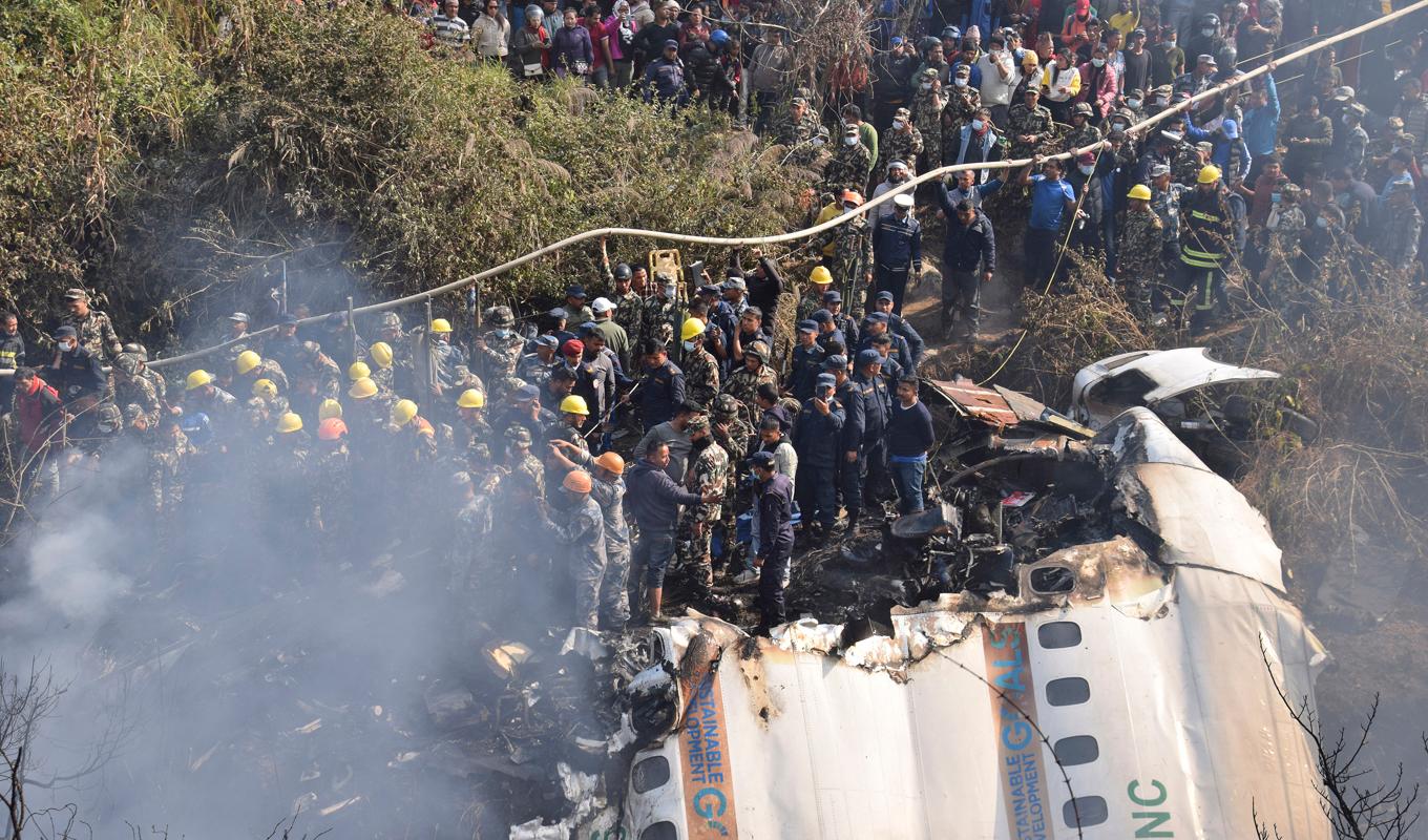 Räddningstjänst och lokalinvånare samlade kring passagerarplanet som kraschat i staden Pokhara i Nepal. Foto: Krishna Mani Baral