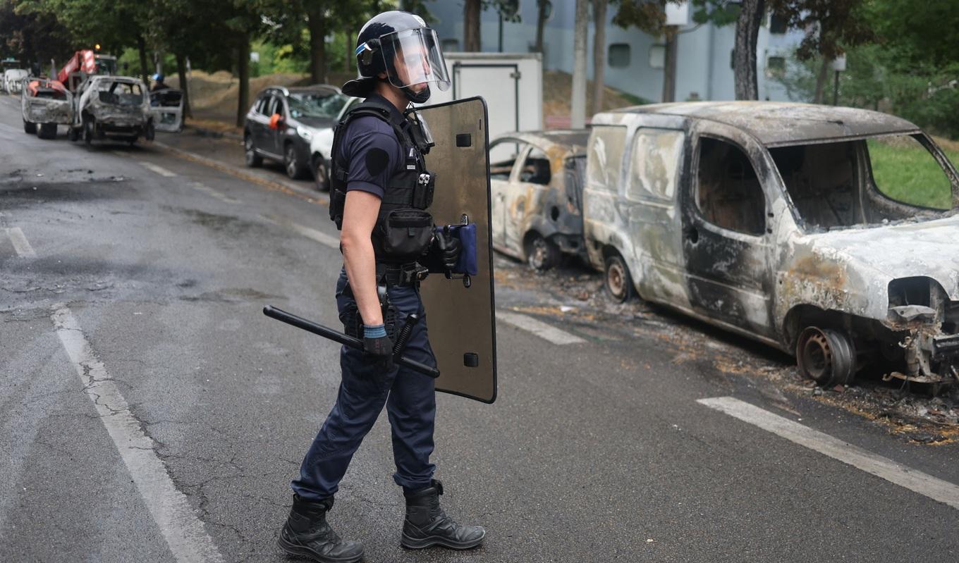 En fransk polis vid utbrända bilar i Nanterre utanför Paris den 1 juli 2023. Foto: Charly Triballeau/AFP via Getty Images