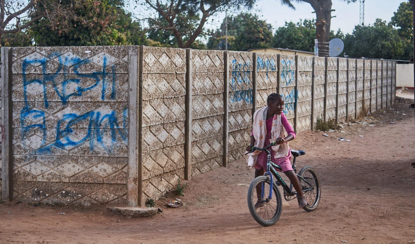 En flicka på cykel framför en mur i Chitungwiza, Zimbabwe, där någon klottrat en uppmaning om nyval efter det hårt kritiserade valet. Foto: Zinyange Auntony/AFP via Getty Images