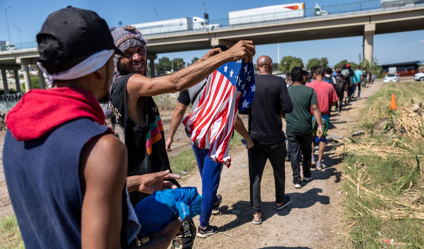 En migrant från Venezuela håller upp en amerikansk flagga efter att ha tagit sig från Mexiko till Rio Grande i delstaten Texas i USA den 28 september 2023. Foto: John Moore/Getty Images