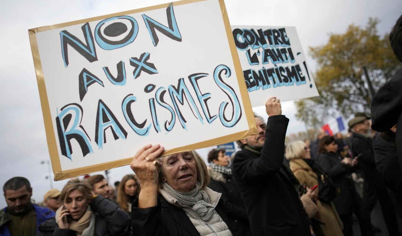 Nej till rasism, står det på kvinnans plakat under en demonstration mot antisemitism i Paris under lördagen. Foto: Christophe Ena/AP/TT