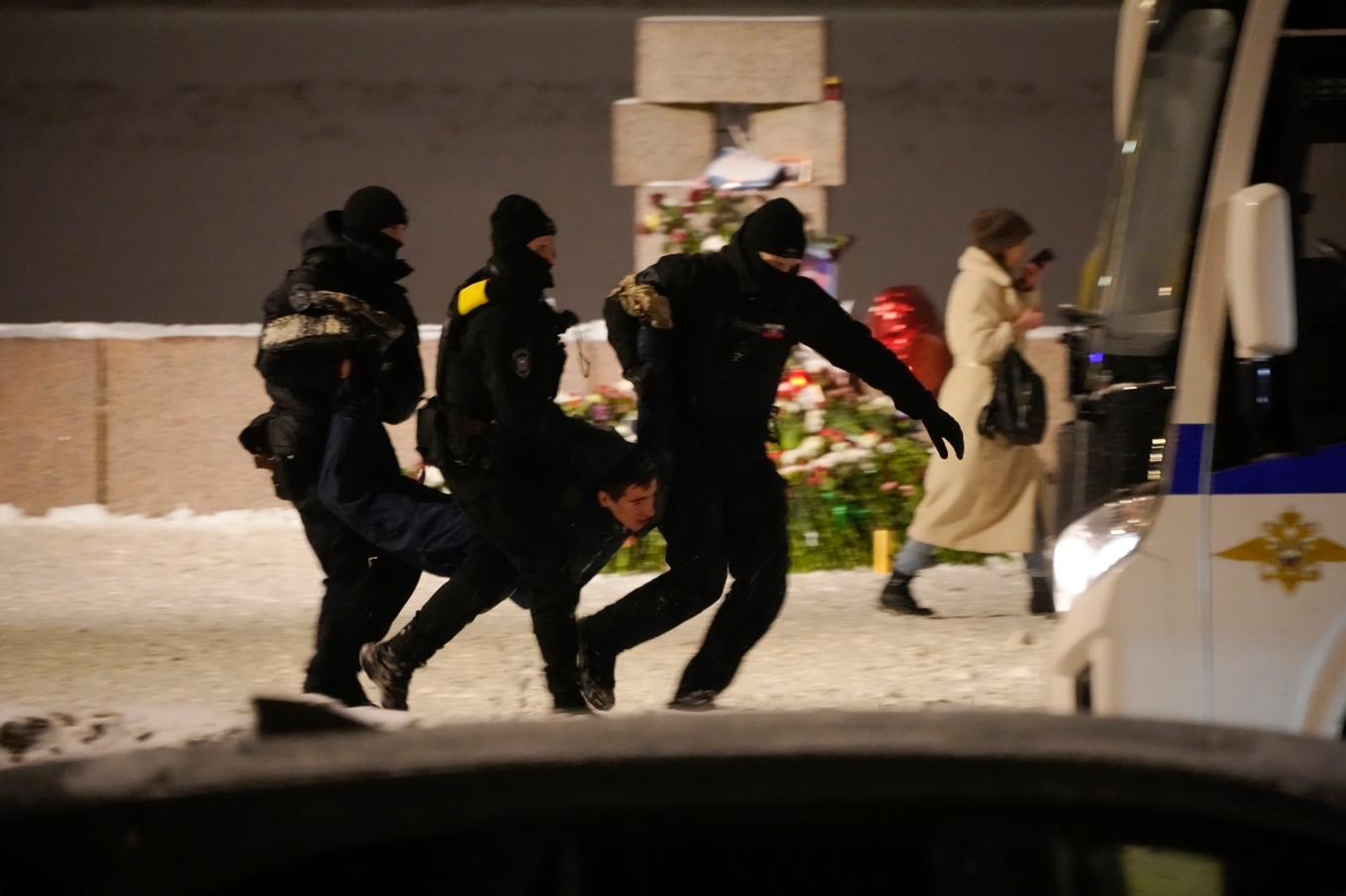 Polis i S:t Petersburg bär bort en man som lagt blommor vid ett monument för att hedra Aleksej Navalnyj. Bild från i fredags. Foto: AP/TT