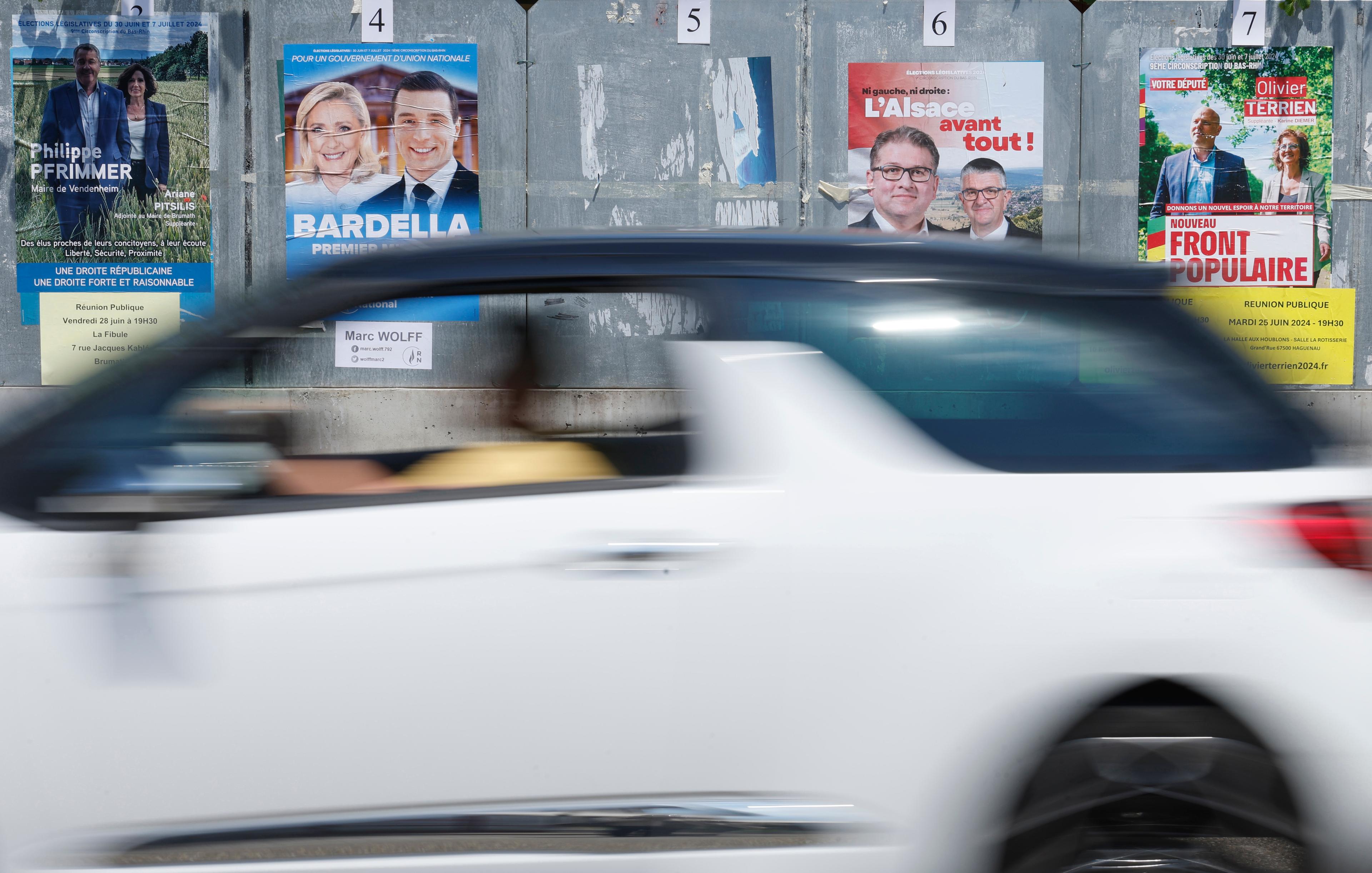 Personer går förbi valaffischer i Strasbourg inför söndagens extrainsatta parlamentsval i Frankrike. Bild från tidigare i veckan. Foto: Jean-Francois Badias/AP/TT