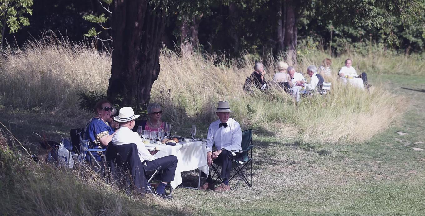 Glyndebourne har en strikt klädkod: Herrarna ska bära smoking, punkt slut. Sedan spelar det ingen roll om högsommarvärmen slår till med full kraft. Herrarna i hagen får läska sig så gott det går med champagne och Pimm’s. Gästande damer kan bära sommaraktig cocktailklänning. Foto: Oli Scarff/Getty Images