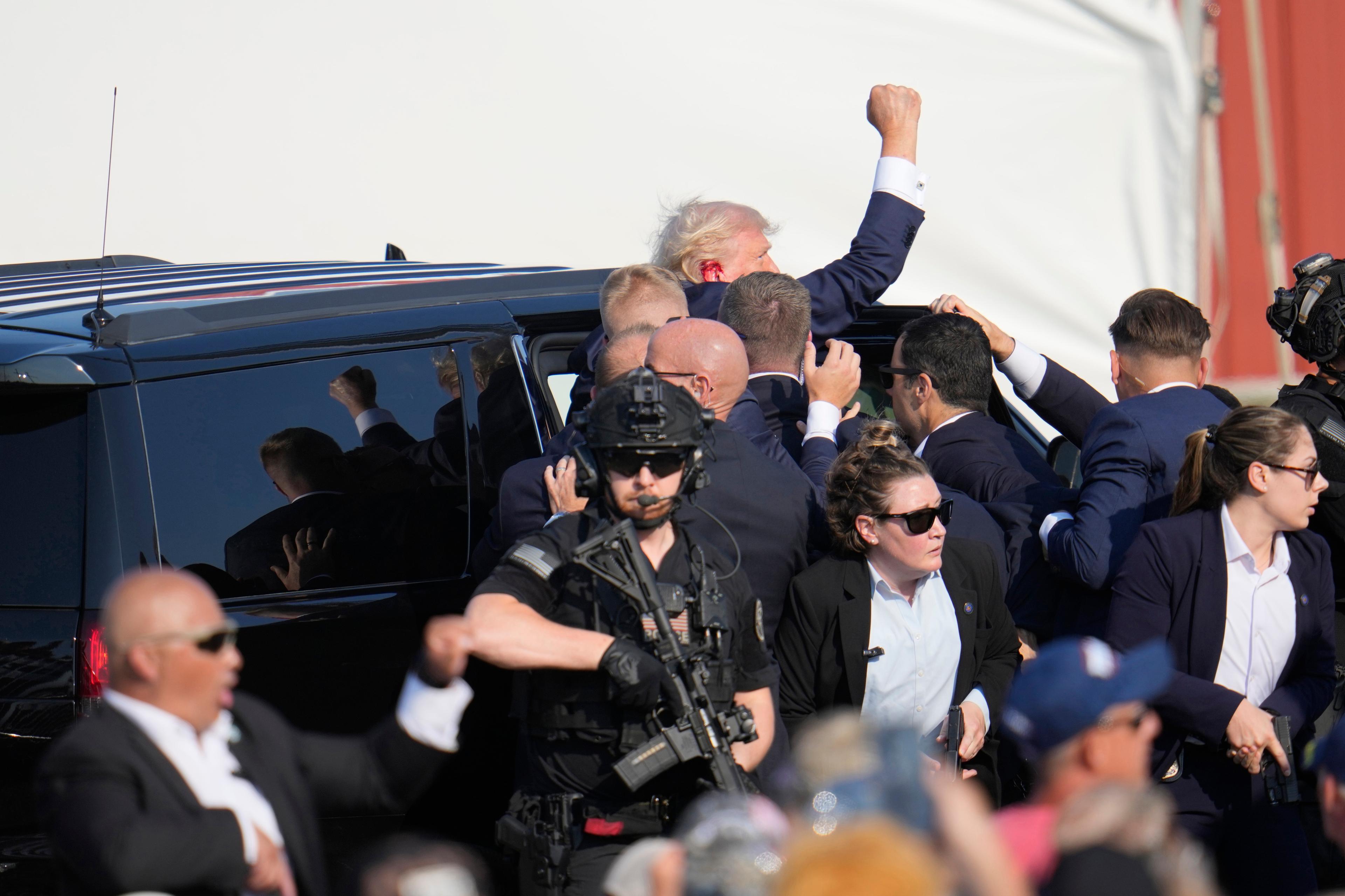 Republikanen och expresidenten Donald Trump förs in i en bil efter mordförsöket mot honom under ett politiskt massmöte i Butler i Pennsylvania. Foto: Gene J. Puskar/AP/TT