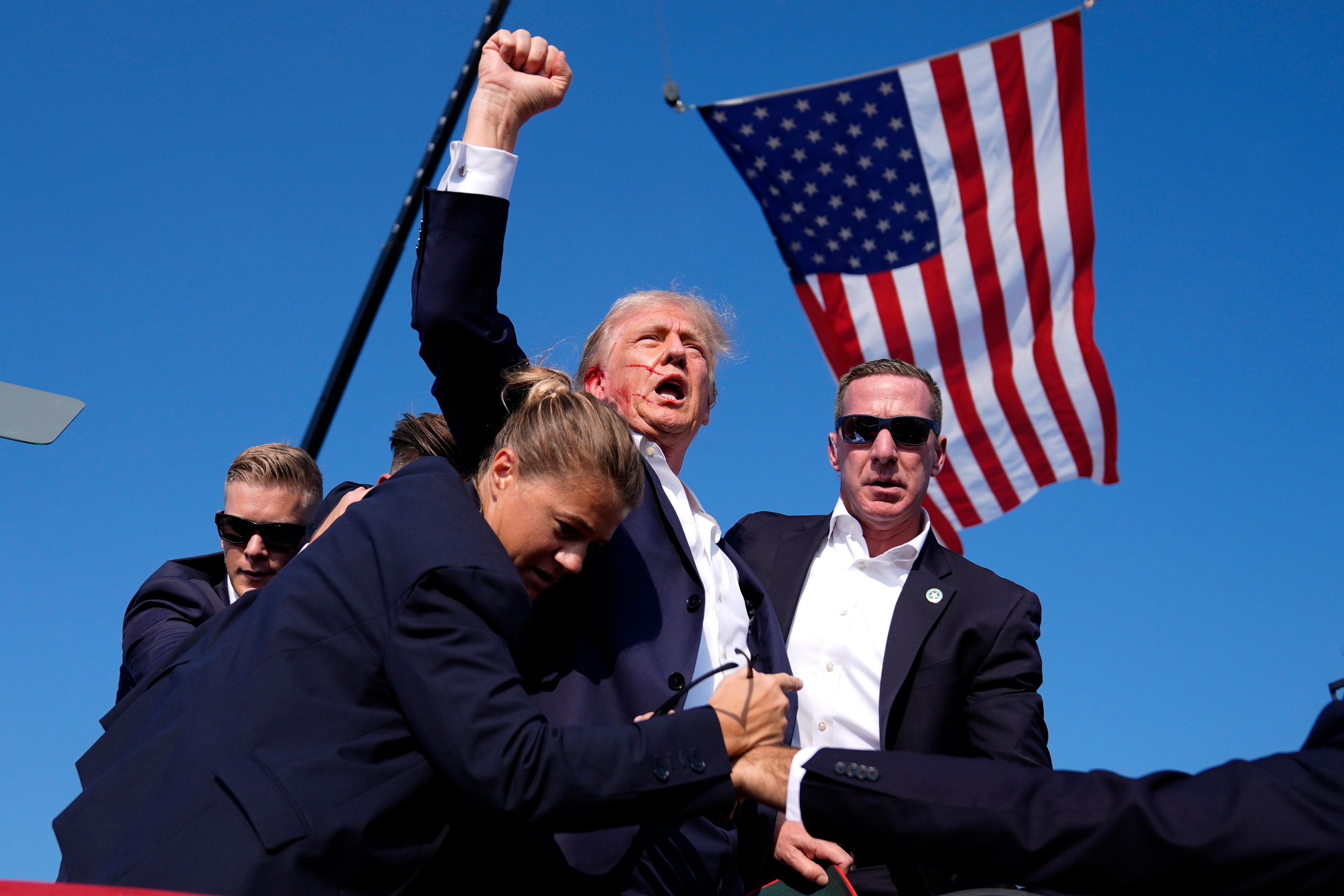 President Donald Trump omringad av vakter när han lämnar scenen efter att ha utsatts för ett mordförsök i Butler, Pennsylvania, den 13 juli. Foto: Evan Vucci/AP