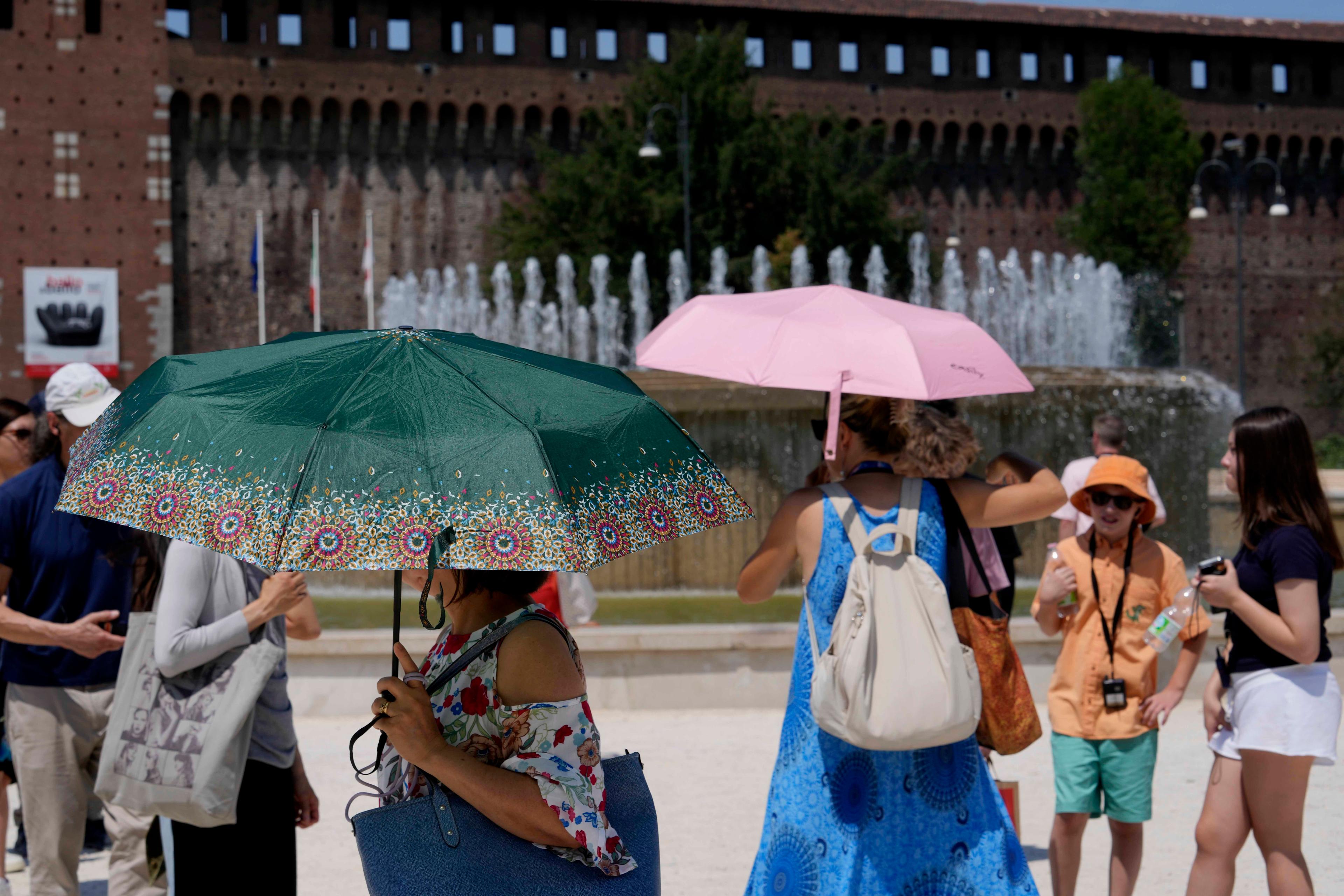 Turister skyddar sig mot hettan. Värmen har fått bränder att bryta ut i Italien. Arkivbild. Foto: Luca Bruno/AP/TT