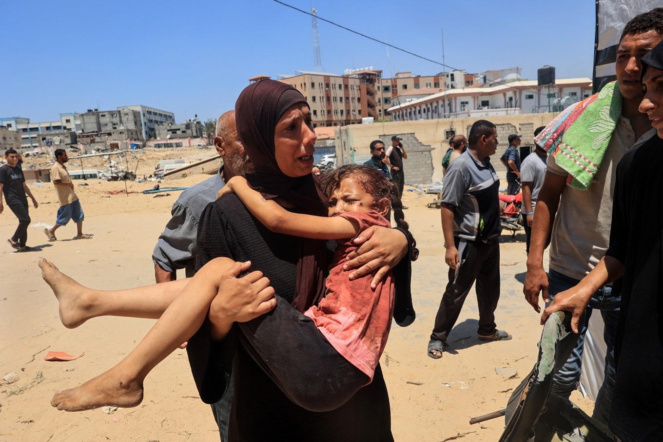 En palestinsk kvinna bär ett skadat barn till Nasser-sjukhuset i Gaza den 13 juli. Putin kommer inte i närheten av den granskning eller den kritik som Israel hanterar, menar Lotta Gröning. Foto: Eyad Baba/AFP via Getty Images