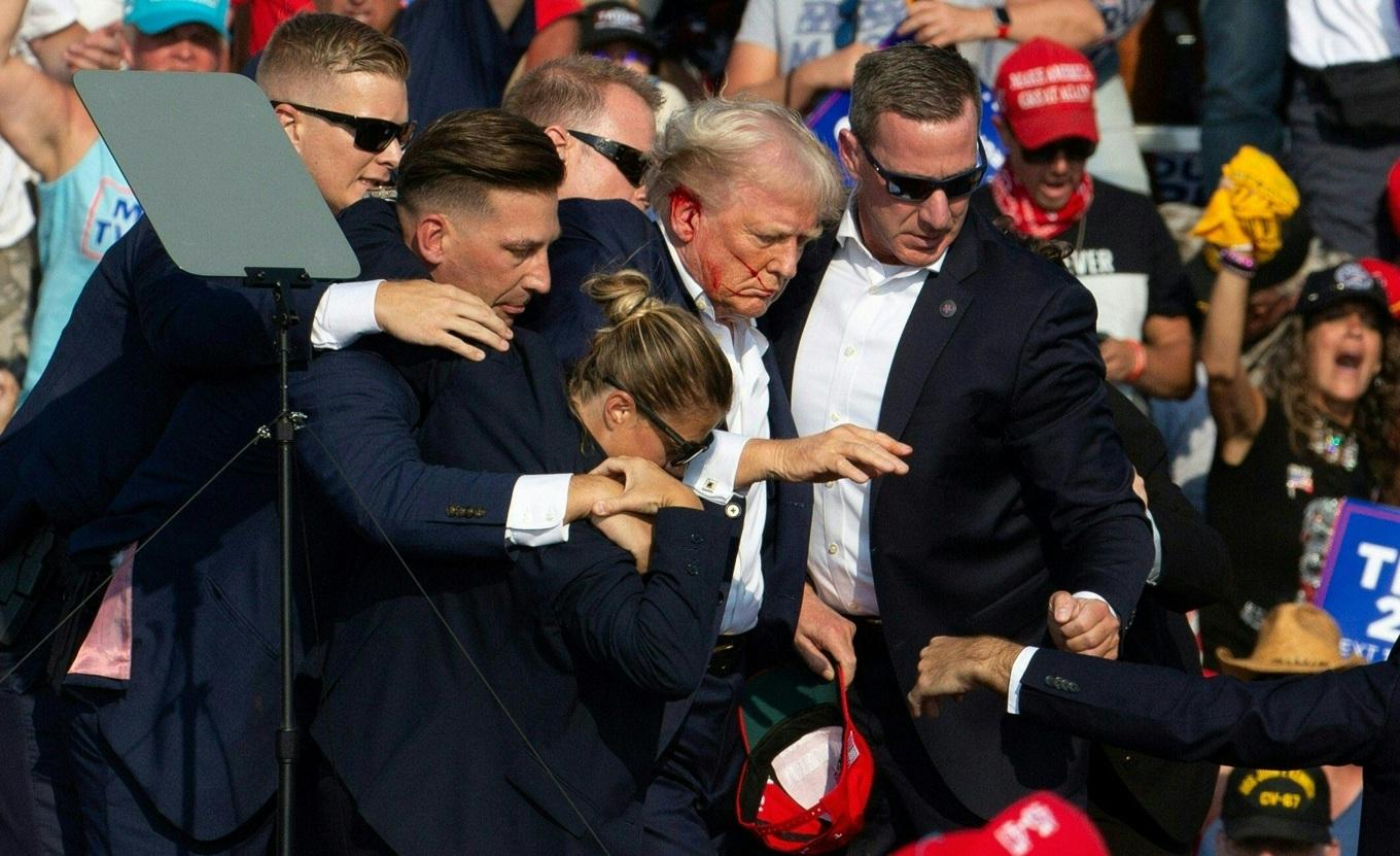 Den republikanske presidentkandidaten Donald Trump tas av scenen av säkerhetspersonal vid ett kampanjevenemang i Butler, Pennsylvania, den 13 juli. Donald Trump träffades i örat i ett mordförsök av en beväpnad man vid ett kampanjmöte i lördags. Bild: REBECCA DROKE/AFP via Getty Images.