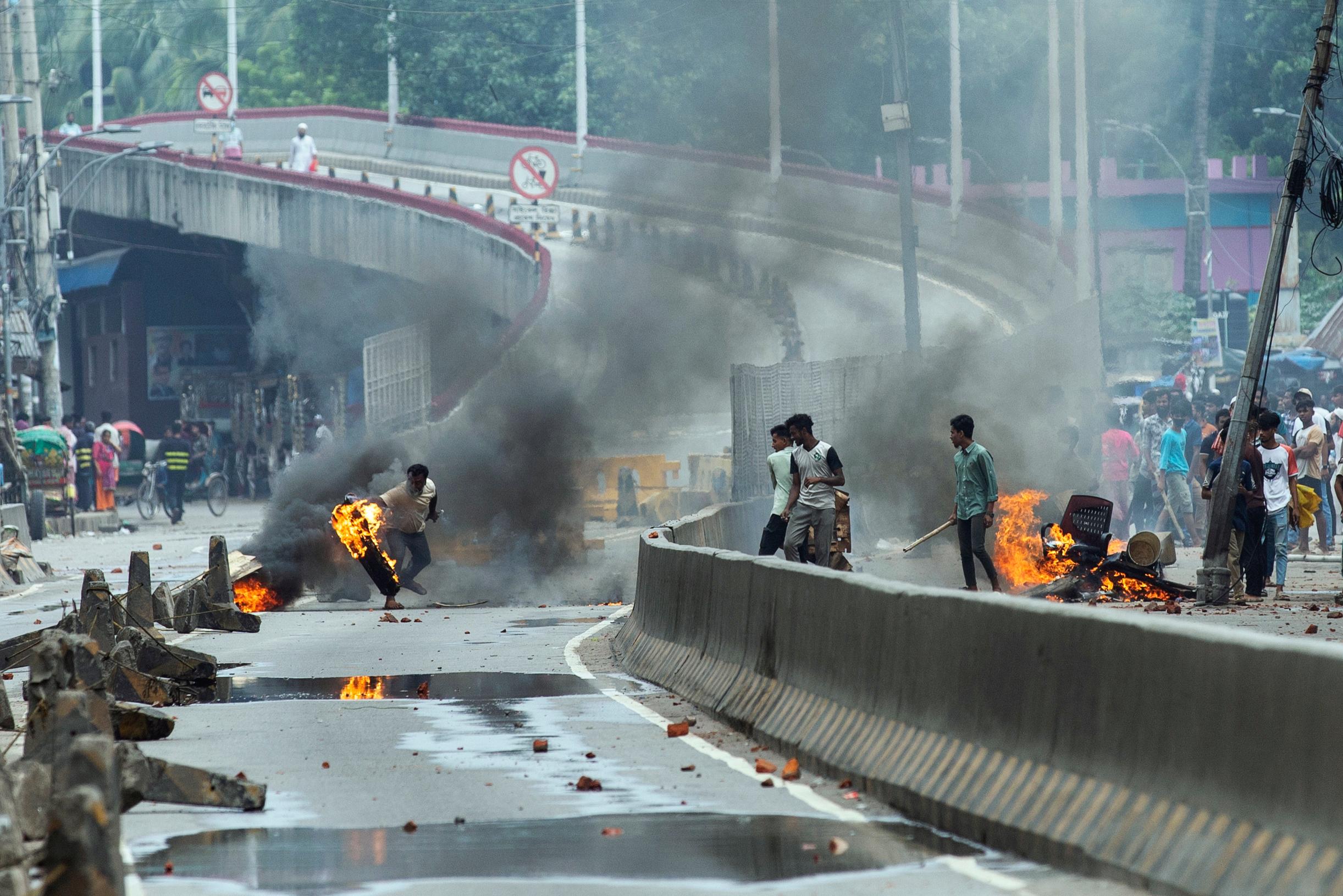 En demonstrant kastar ett brinnande däck under måndagens våldsamma protester i Bangladesh huvudstad Dhaka. Foto: Rajib Dhar/AP/TT