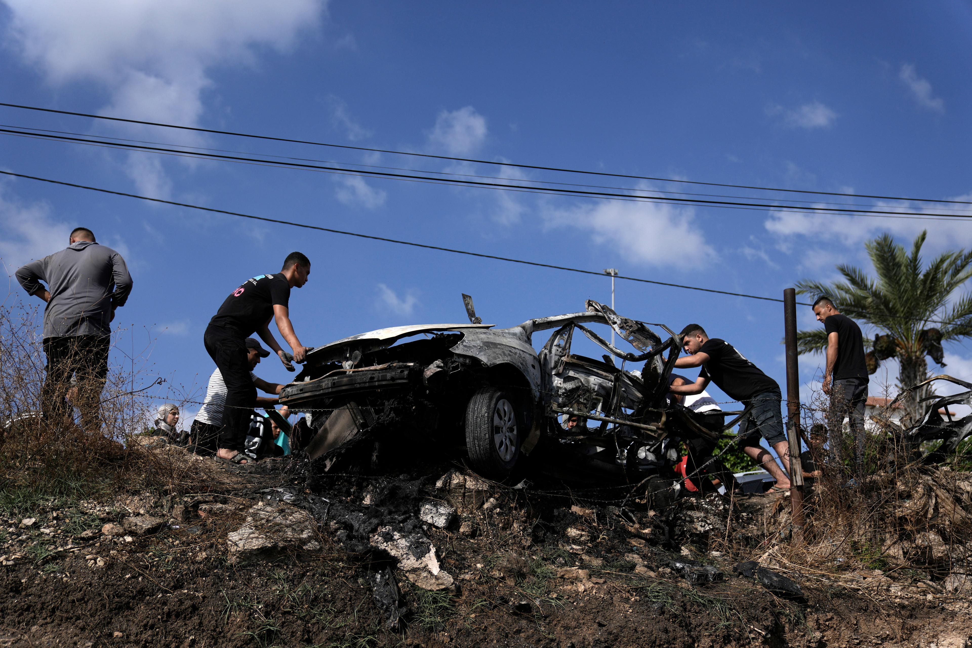 Palestinier samlas runt en bil som träffats av en israelisk drönarattack i byn Zaita på Västbanken. Bild från den gångna helgen. Foto: Majdi Mohammed/AP/TT