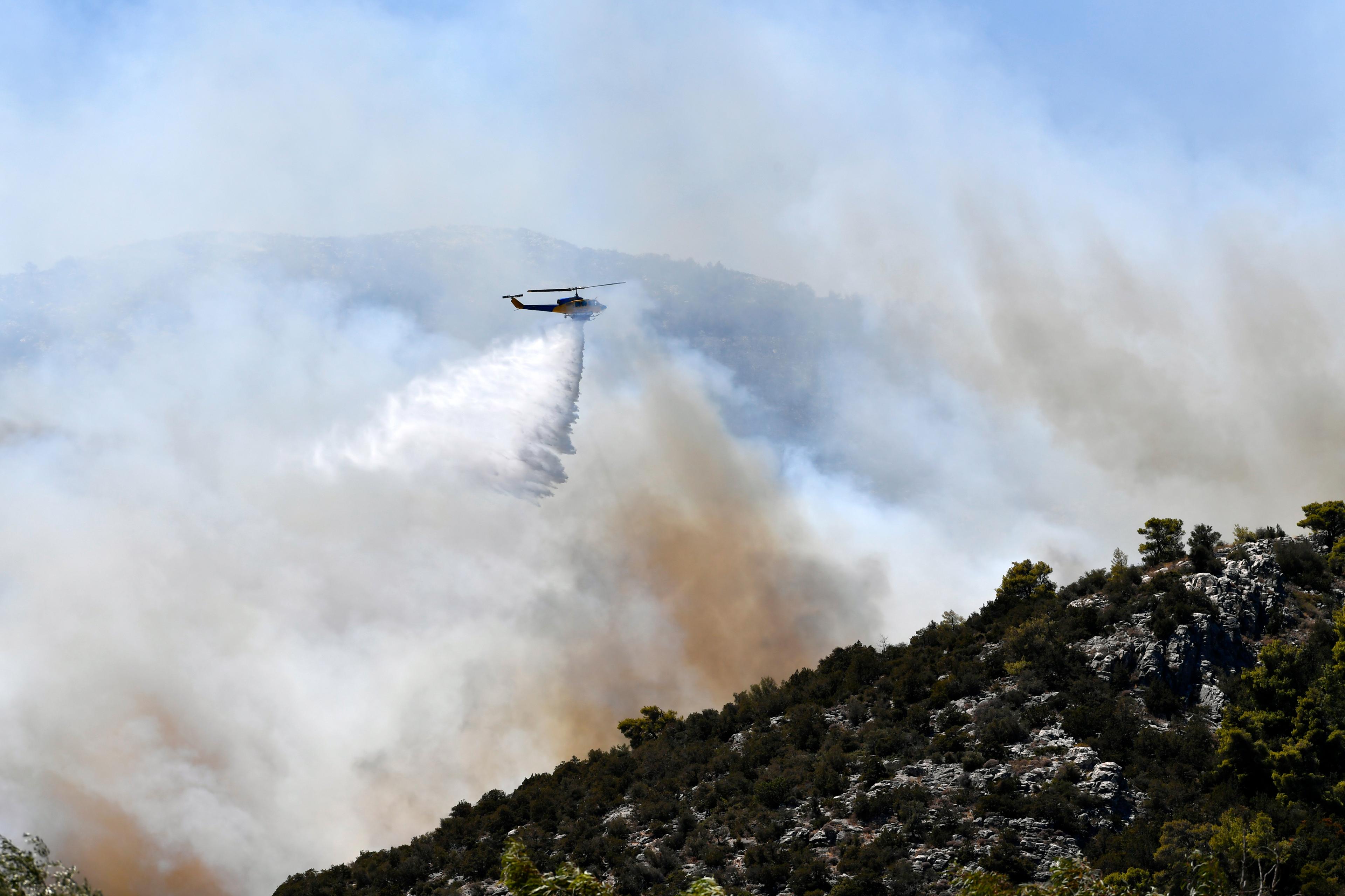 En helikopter bekämpar skogsbranden i Nea Makri, öster om Aten, under måndagen. Foto: Michael Varaklas/AP/TT