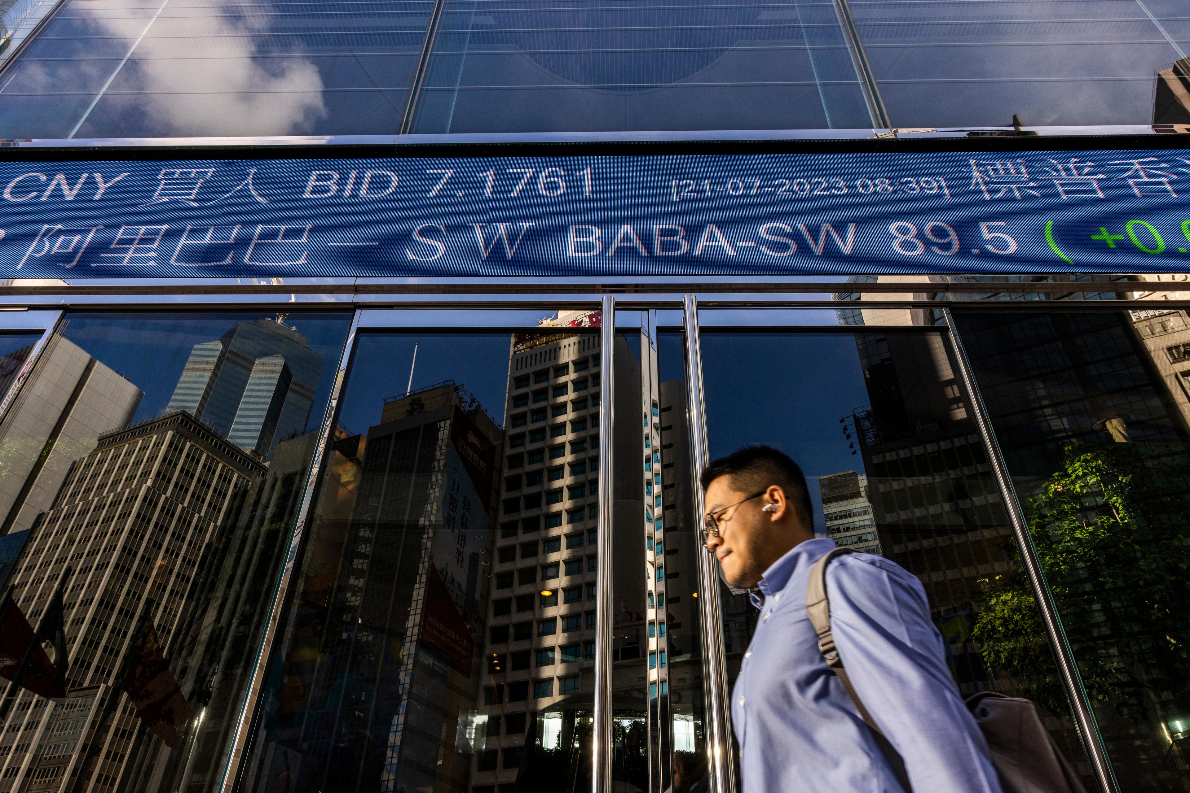 En man passerar skärmen med data för Hongkong-börsen. Arkivbild. Foto: Louise Delmotte/AP/TT