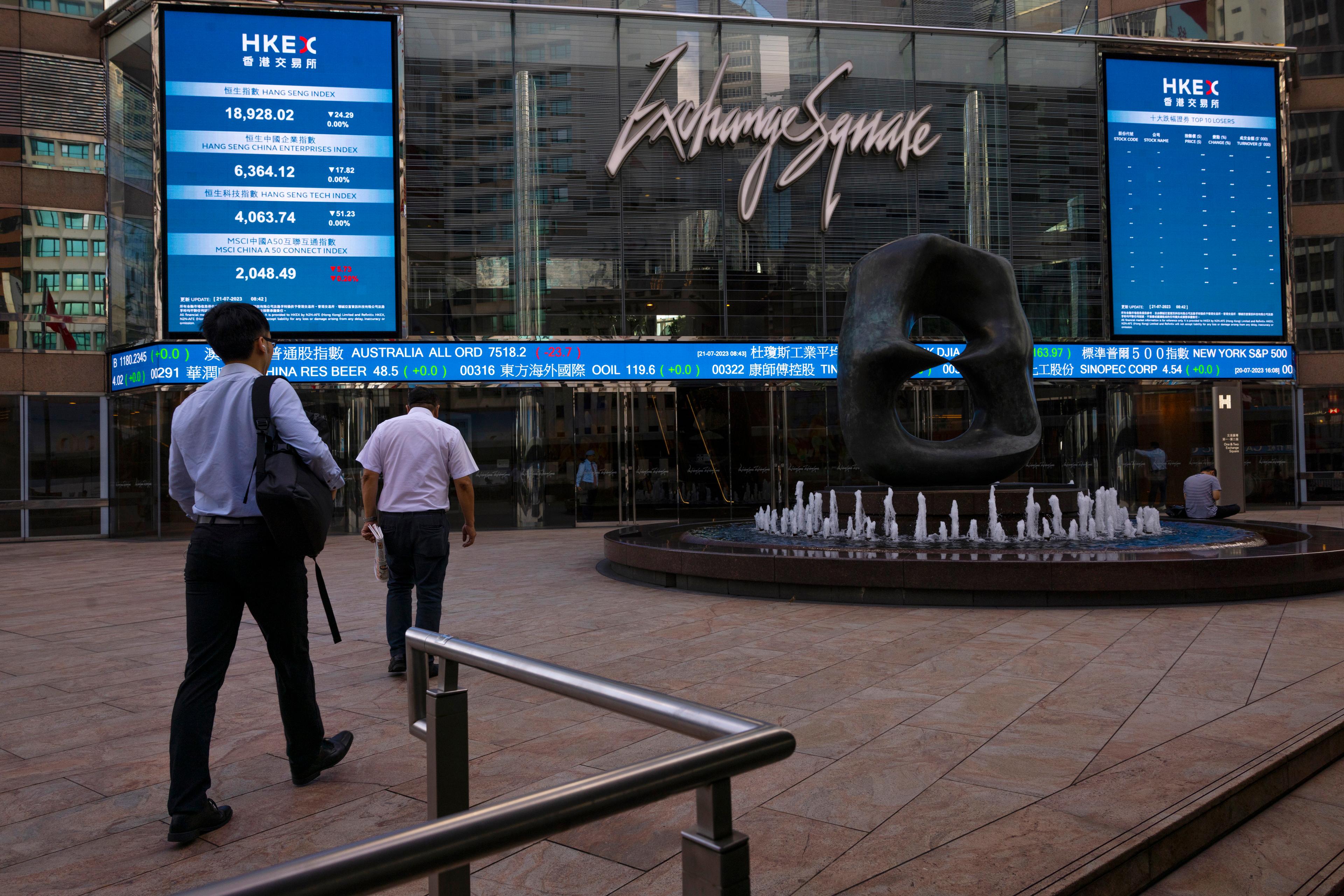 Människor passerar en elektronisk anslagstavla för Hongkong-börsen. Arkivbild. Foto: Louise Delmotte/AP/TT