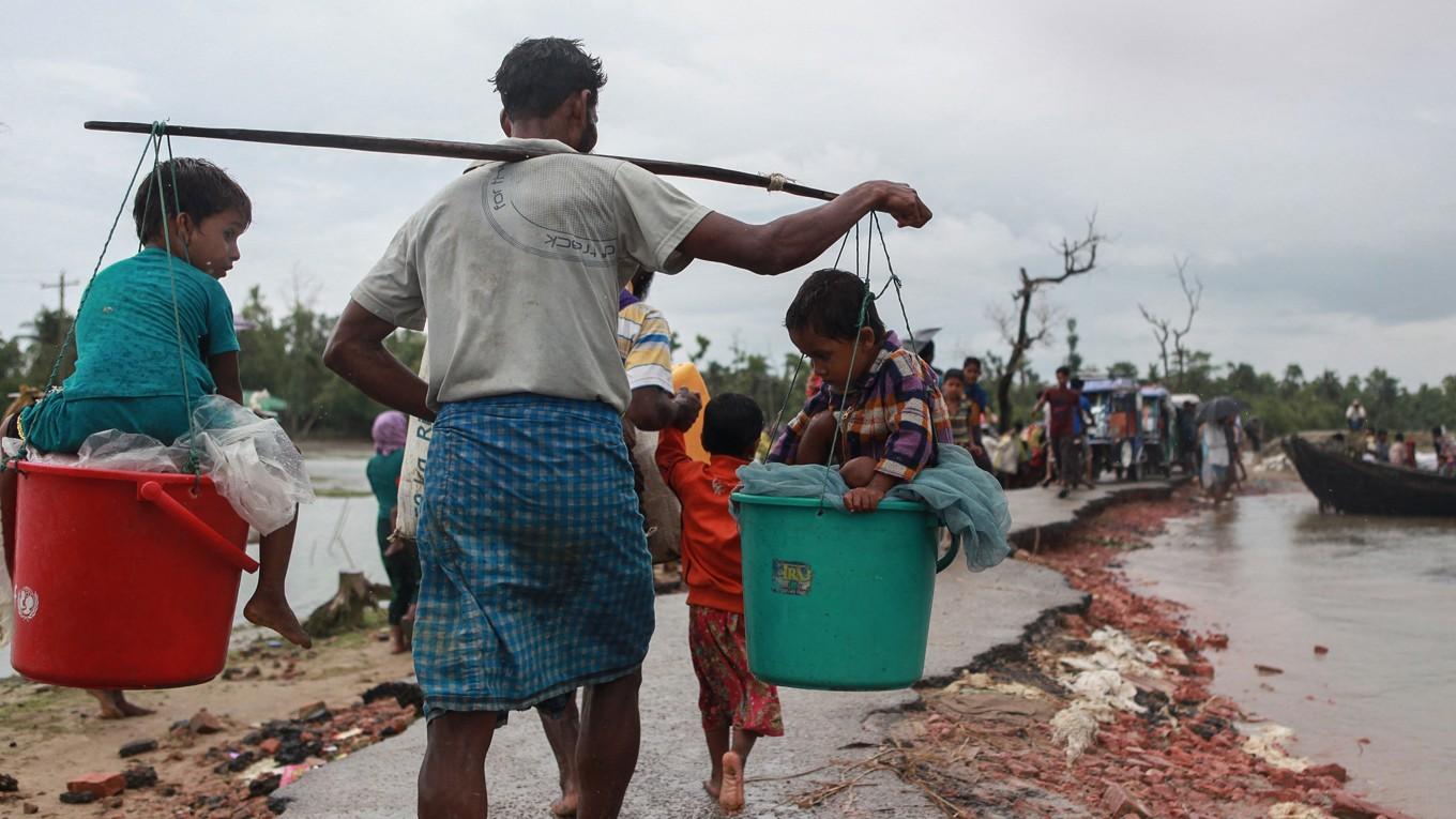 En rohingya-flykting bär två barn i hinkar när de anländer till Shah Porir Dwip, Teknaf i Bangladesh den 9 september 2017, på flykt från våldet i grannlandet Myanmar. Enligt Förenta Nationerna är rohingyafolket en av världens mest förföljda folkgrupper, och FN-tjänstemän har beskrivit förföljelsen av rohingyafolket som etnisk rensning. Foto: Emrul Kamal/AFP Via Getty Images