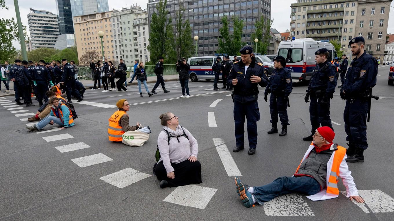 Österrikiska poliser talar med aktivister från miljörörelsen Sista generationen (Letzte Generation) i samband med att man blockerar trafiken i Wien i Österrike den 3 april 2023. Foto: Joe Klamar/AFP via Getty Images