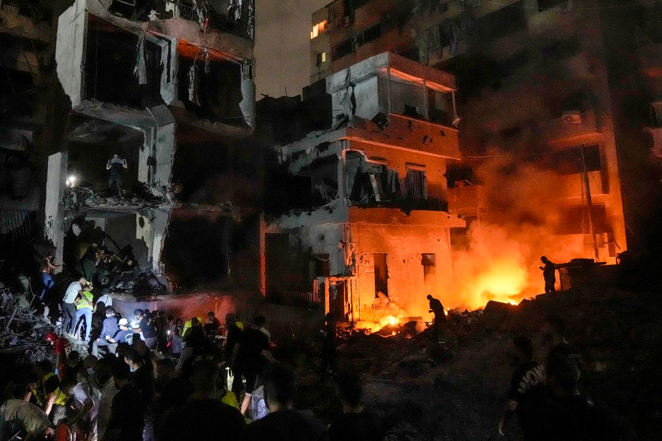 Människor samlas framför en byggnad som förstörts i ett israeliskt flyganfall i centrala Beirut. Foto: Bilal Hussein/AP/TT