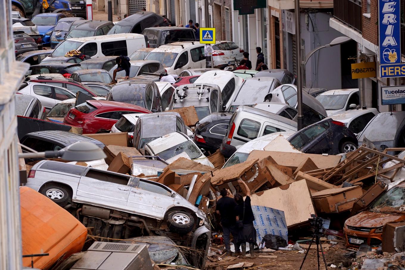 Bilar ligger huller om buller efter att ha svepts med i vattenmassorna i Valencia. Foto: Alberto Saiz/AP/TT