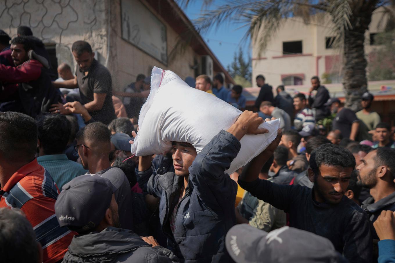 Palestinier i Dayr al-Balah i Gaza tar emot hjälp från Unrwa. En man bär iväg en säck med mjöl. Bilden togs i lördags. Foto: Abdel Kareem Hana/AP/TT