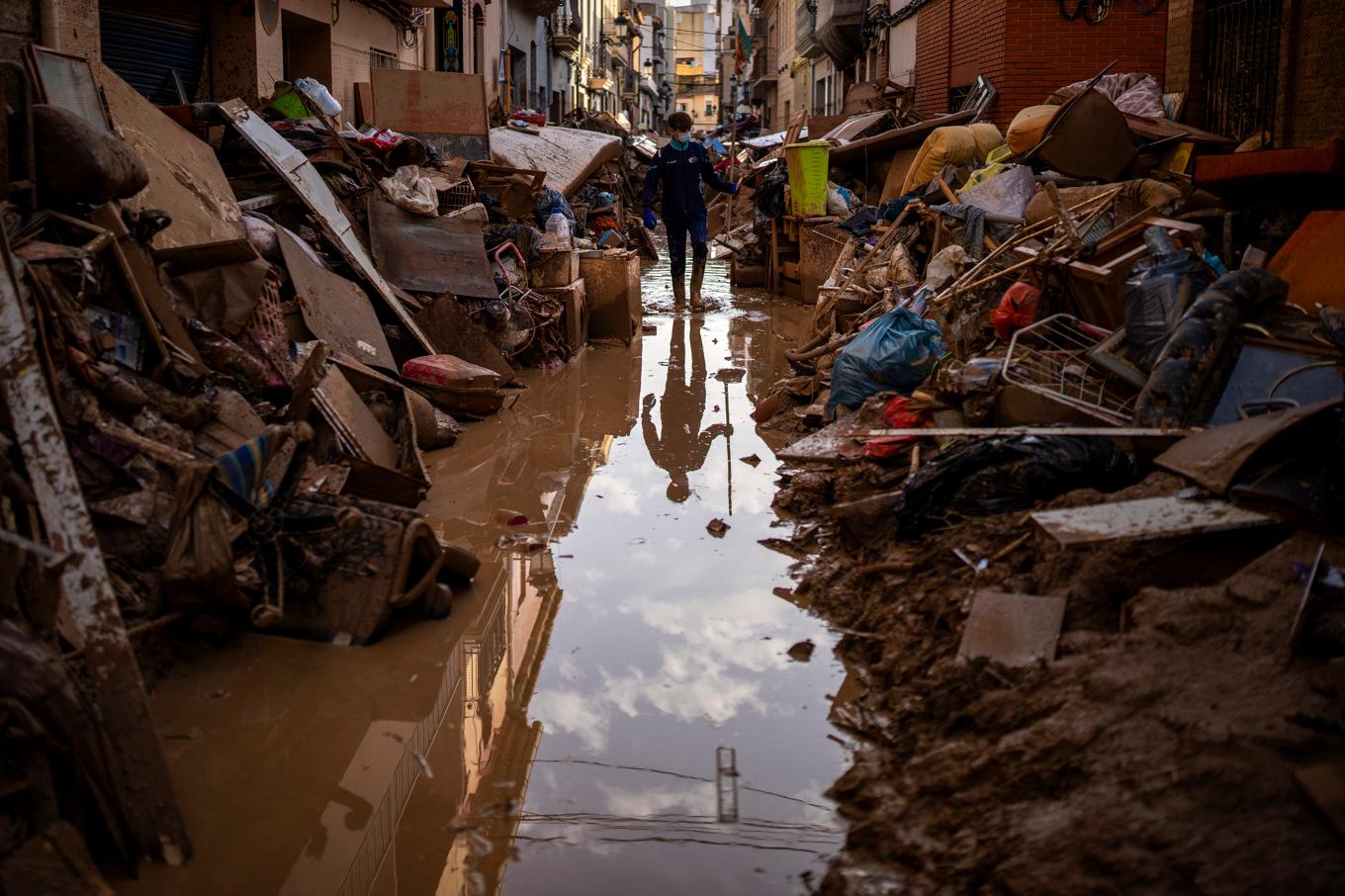 En person går på en gata i staden Paiporta i Valencia där möbler och bråte har samlats. Foto: Emilio Morenatti/AP/TT