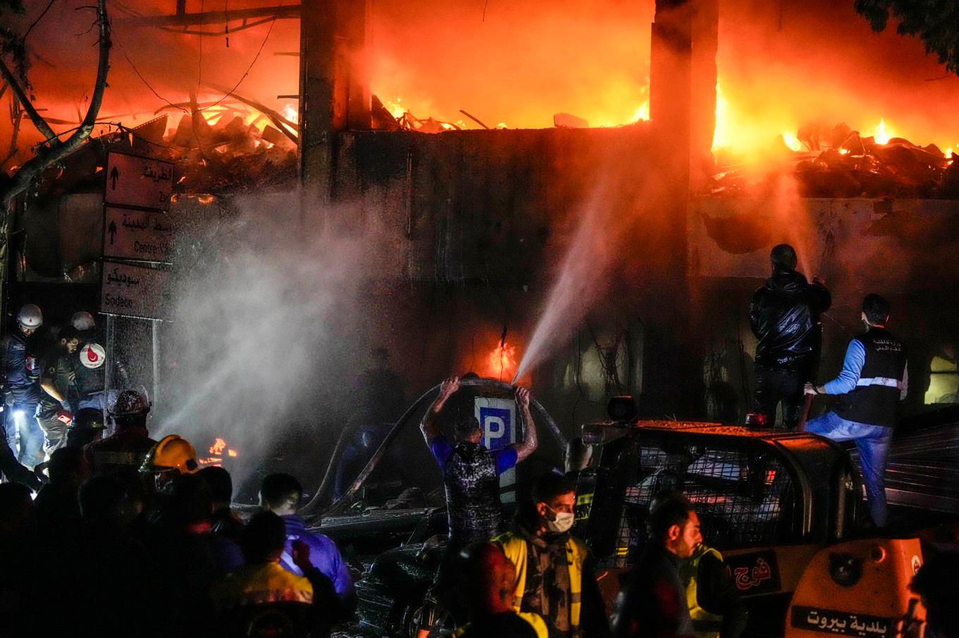 Civilförsvar försöker släcka en brand efter ett av Israels angrepp mot Beirut under söndagen. Foto: Hassan Ammar/AP/TT