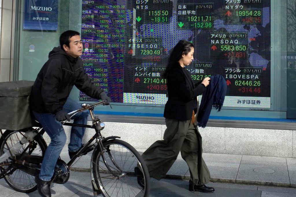 Människor passerar utanför en börsskylt i Tokyo. Foto: Shuji Kajiyama/AP/TT-arkivbild