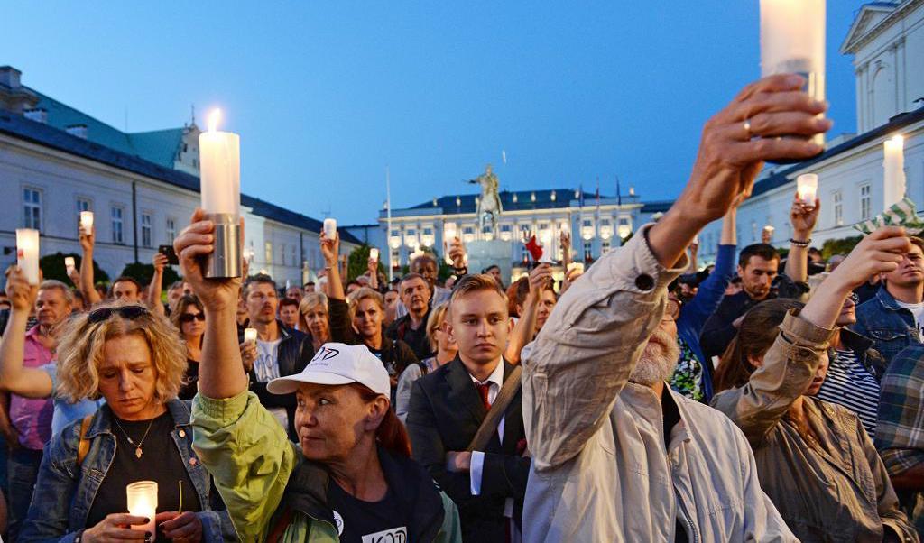 
Människor håller ljus i händerna framför presidentpalatset i Warszawa, i protest mot de nya lagförslagen. Foto: Alik Keplicz/AP/TT                                            