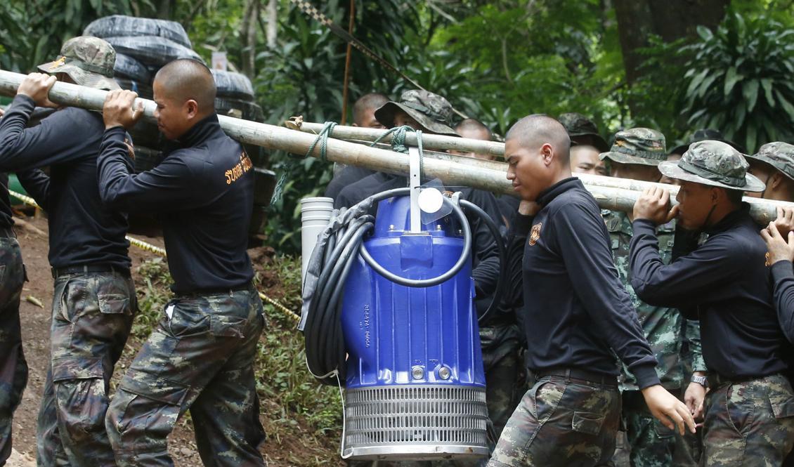 

Soldater bär pumpar som används för att pumpa ut vatten ur grottan där det thailändska pojklaget i fotboll sitter fångna tillsammans med sin tränare. Foto: Sakchai Lalit /AP/TT                                                                                        